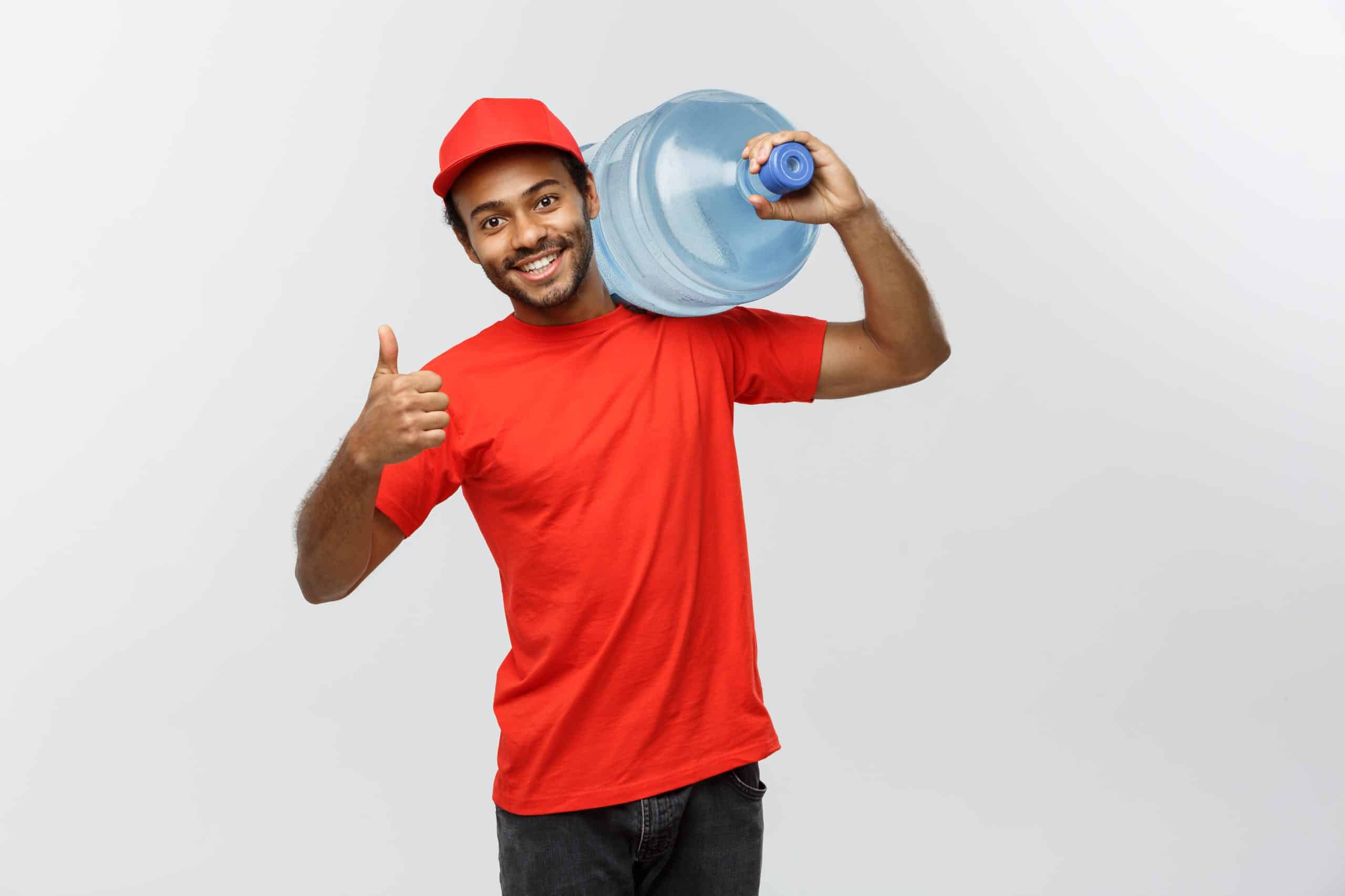 delivery concept handsome african american delivery man holding water tank isolated grey studio background copy space scaled